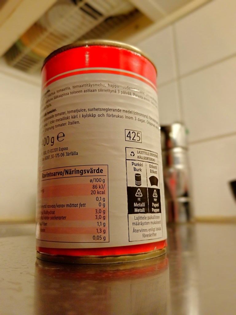 A can of chopped tomatoes with nutritional information and recycling symbols displayed on its label.